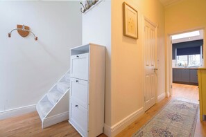 Un escalier avec un mur blanc, une porte et un couloir menant à une cuisine.