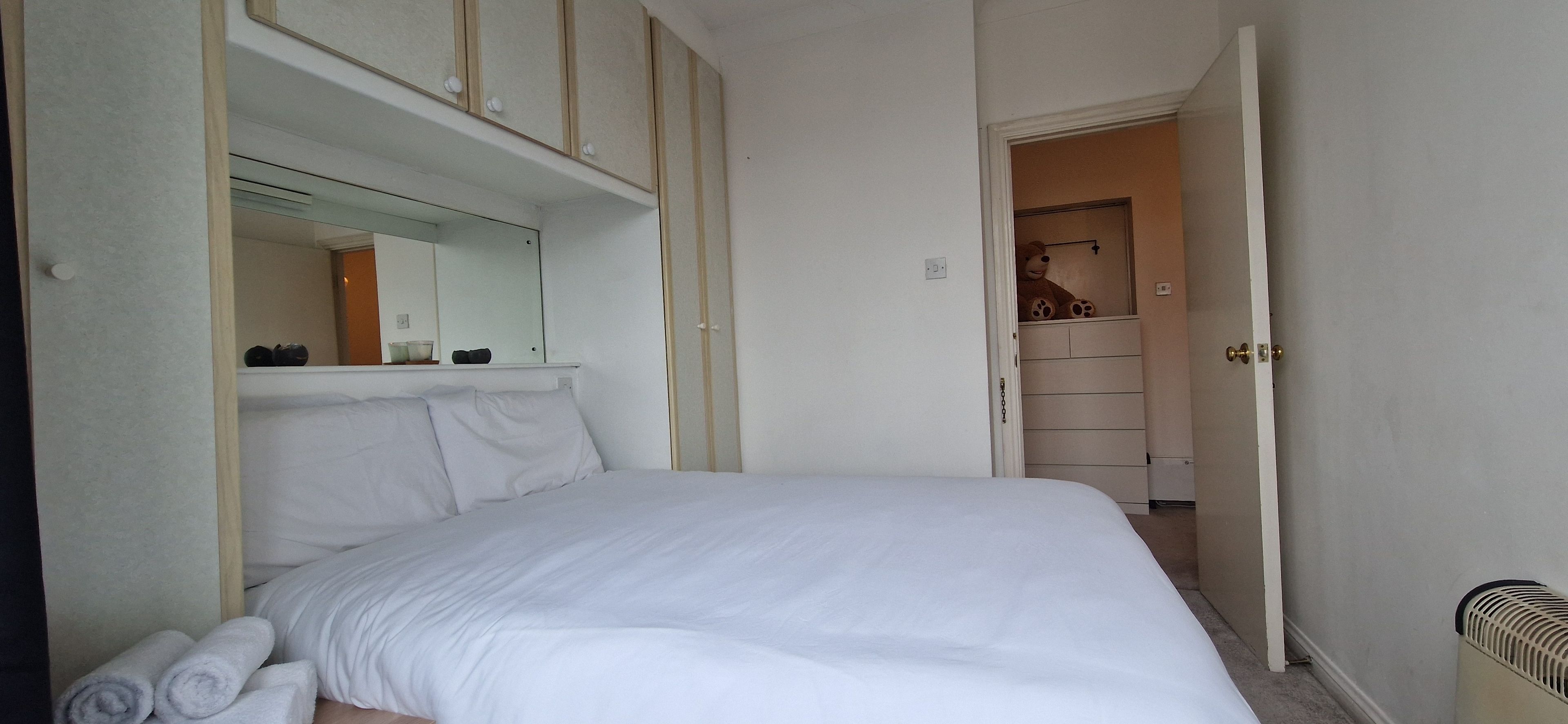 Un dormitorio con cama, armario y espejo.