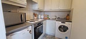 A compact kitchen with a refrigerator, stove, oven, and washing machine.