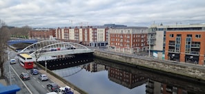 Un río con un puente, un autobús rojo y edificios a lo largo de la orilla.