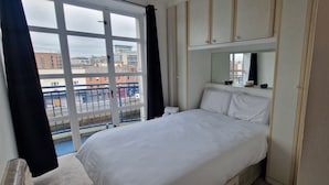 Une chambre d’hôtel avec un lit, une grande fenêtre et une vue sur les bâtiments environnants.