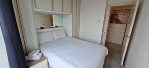A bedroom with a bed, a bedside table with towels, a mirror, and a wardrobe. - Waterfront 2BD Flat with Balcony, Central Dublin (Dublin)