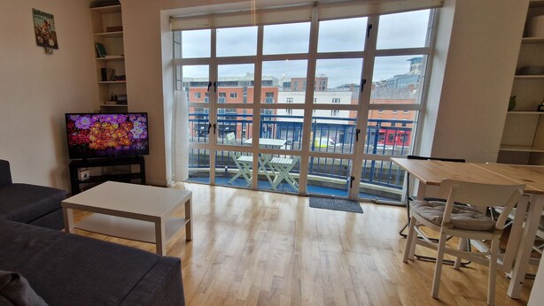 Un salon comprenant un canapé, une table basse, un téléviseur et offrant une vue sur l’extérieur grâce à de grandes fenêtres.