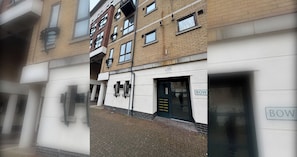 A multi-story building with a ground-level entrance, a sign indicating CCTV, and a door labeled 'BOW'. - Riverside 2BD Flat, Short Walk to the ExCel Centre (Greater London)