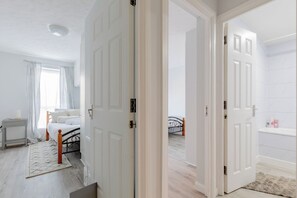 A bedroom with a bed, bedside table, and a window with curtains. - Riverside 2BD Flat, Short Walk to the ExCel Centre (Greater London)