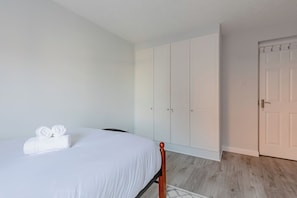 A bedroom with a bed, white wardrobe, and a door. - Riverside 2BD Flat, Short Walk to the ExCel Centre (Greater London)