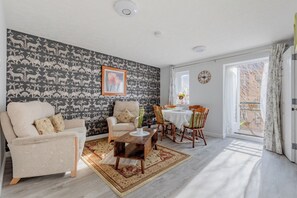 En stue med tapet, en sofa, et sofabord og et spiseområde med stole og et bord.