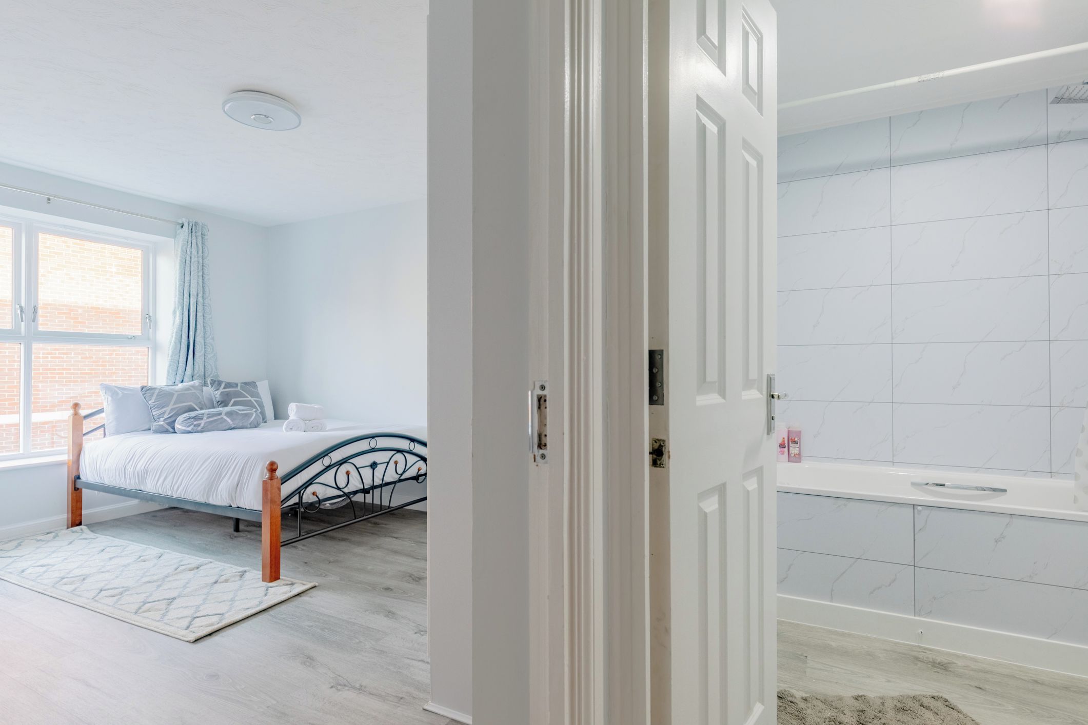 Une chambre à coucher avec un lit, une fenêtre, une salle de bain avec une baignoire et une porte.