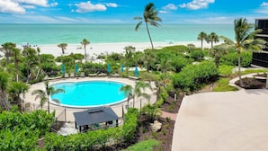 Ein Pool, umgeben von Palmen, mit Blick auf den Strand.