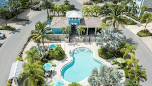 An aerial view of a resort with a swimming pool, palm trees, and a building with a blue roof. - Anglers Bay at One Particular Harbour 392-103 · Lagoon Views · 5-Night Min (Bradenton)