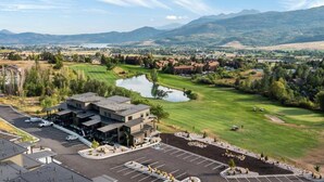 A golf course with a pond, a parking lot, and a building with a modern design.