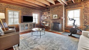 A living room with a fireplace, a television, and a stationary bike.
