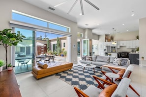 A spacious living area with a sofa, armchairs, a coffee table, and a dining table.