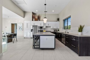 A modern kitchen with a central island, stainless steel appliances, and a large window.