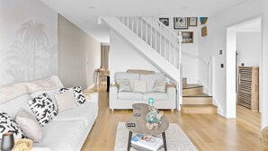 A modern living room with a sofa, coffee table, and a staircase leading to another level. - The Palm Tree Lodge | Spacious contemporary 2 bed (Saint Columb Major)
