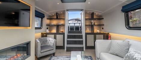 A compact, modern interior with a skylight, a fireplace, a sofa, and a coffee table.