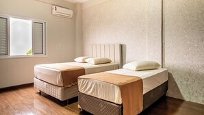 A room with two beds, a window with blinds, an air conditioning unit, and patterned wallpaper. - ARCA'S EXPRESS HOTEL (Toledo)