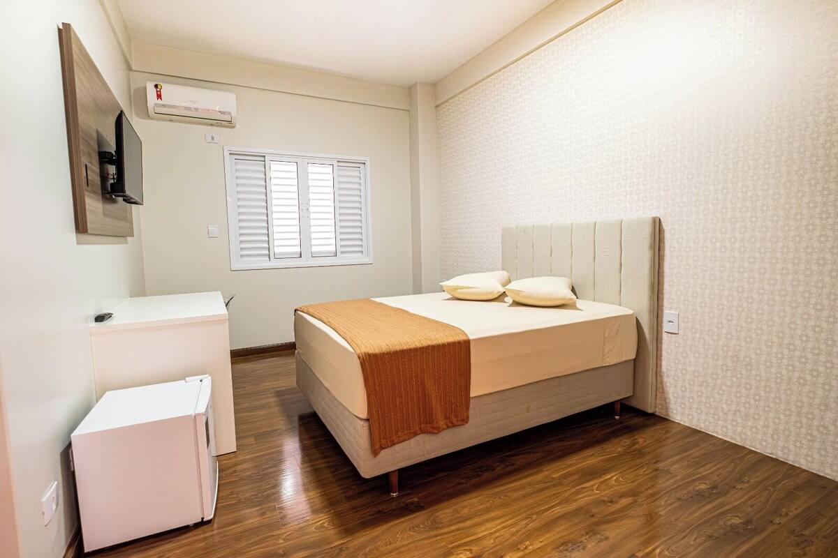 A bedroom with a bed, bedside table, and a small white cabinet.