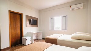 A hotel room with two beds, a desk, a chair, a TV, and a window with shutters. - ARCA'S EXPRESS HOTEL (Toledo)