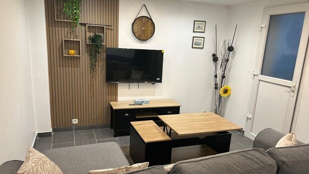 Ett modernt vardagsrum med en soffa, ett soffbord, en tv och ett träskåp.