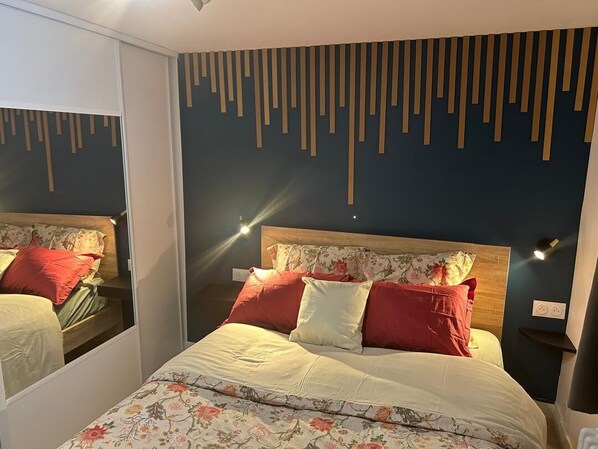A bedroom with a bed, a nightstand, and a wall-mounted light fixture.