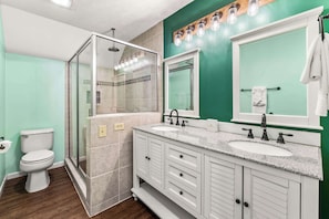 A bathroom with a glass-enclosed shower, a double sink vanity, and a large mirror.