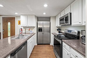 A modern kitchen with stainless steel appliances, white cabinetry, and a granite countertop.