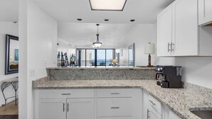A modern kitchen with white cabinets, granite countertops, and a skylight. - 🌴🌞🌴Beachfront Condo | Seasonally Heated Pool | Navarre Towers 1205🌴🌞🌴 (Navarre Beach)