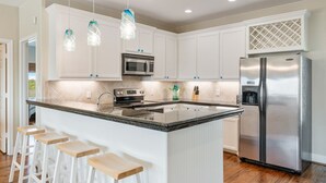 A modern kitchen with white cabinets, stainless steel appliances, and a central island with bar stools.