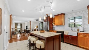 A modern kitchen with a central island, wooden cabinets, and a large window. - Lake Shore Landing – For 20! (Branson)