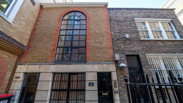 A building with a large arched window, a black door, and a black metal fence. - Great flat near St Pauls Cathedral (London)
