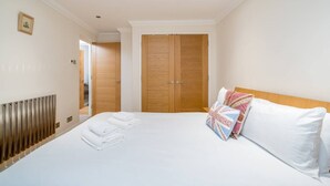 A hotel room with a large bed, a wooden wardrobe, and a radiator. - Great flat near St Pauls Cathedral (London)
