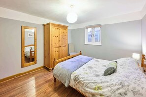 Cozy bedroom with a single bed, floral-patterned bedspread, and a mirror.