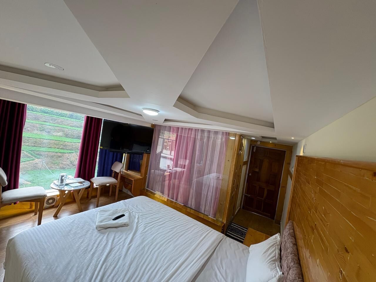 Habitación de hotel con una cama grande, un escritorio, una silla y vistas al exterior.