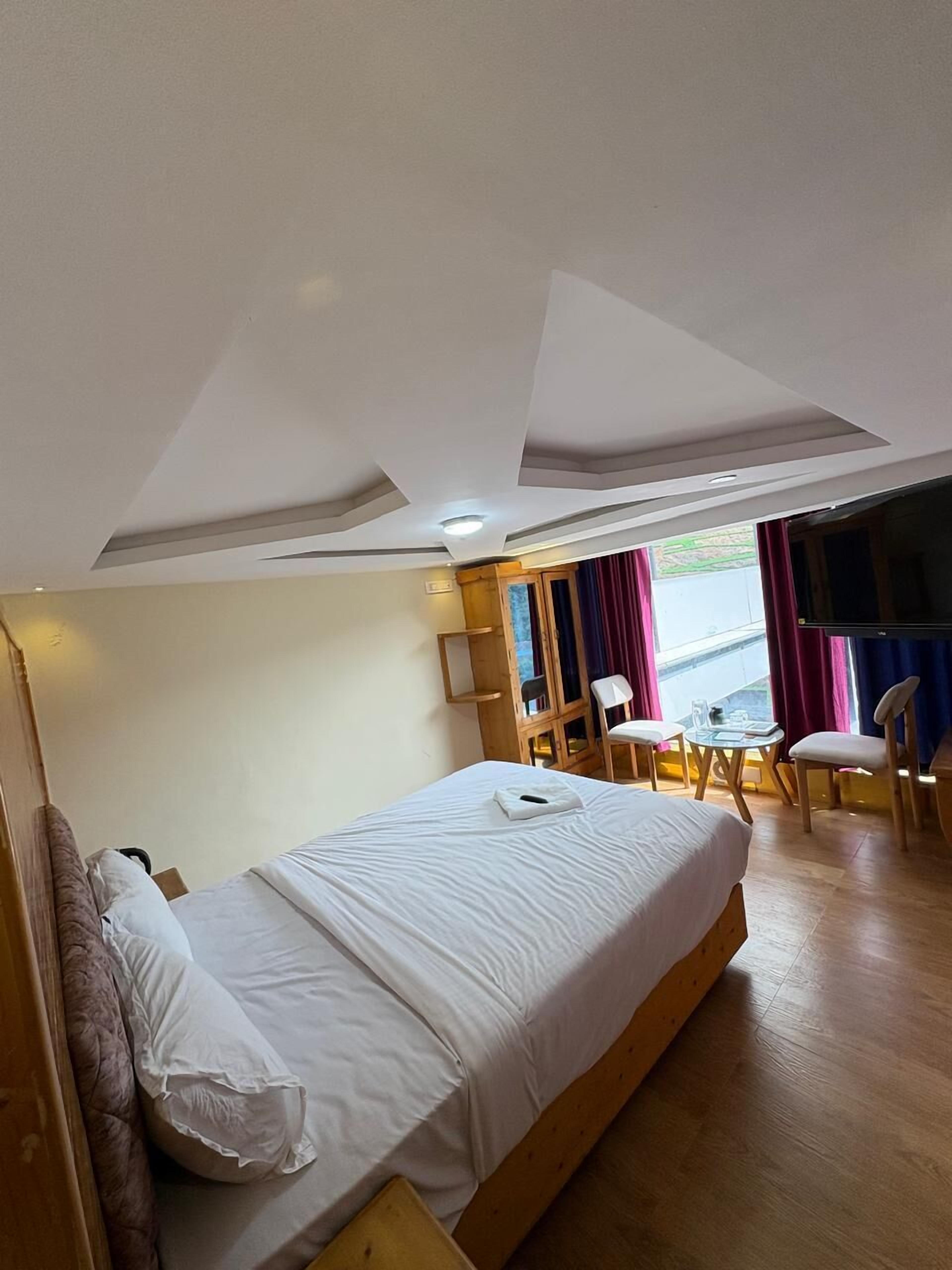 Habitación de hotel con cama, escritorio y silla. Hay una ventana con cortinas.