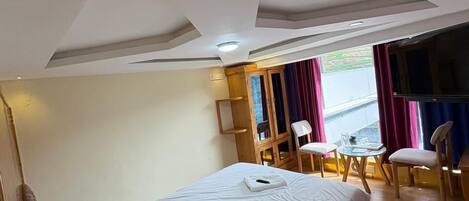 Habitación de hotel con cama, escritorio y silla. Hay una ventana con cortinas.