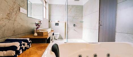 Un baño moderno con una bañera grande, una zona de ducha y un tocador con espejo.