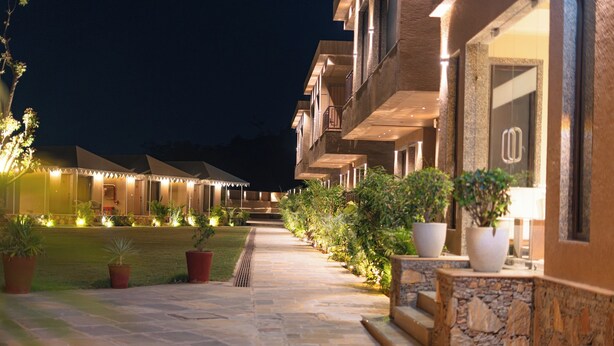 A hotel corridor with multiple rooms, potted plants, and a stone pathway. - Imperia Resort by The Sky Imperial (Nathdwara)