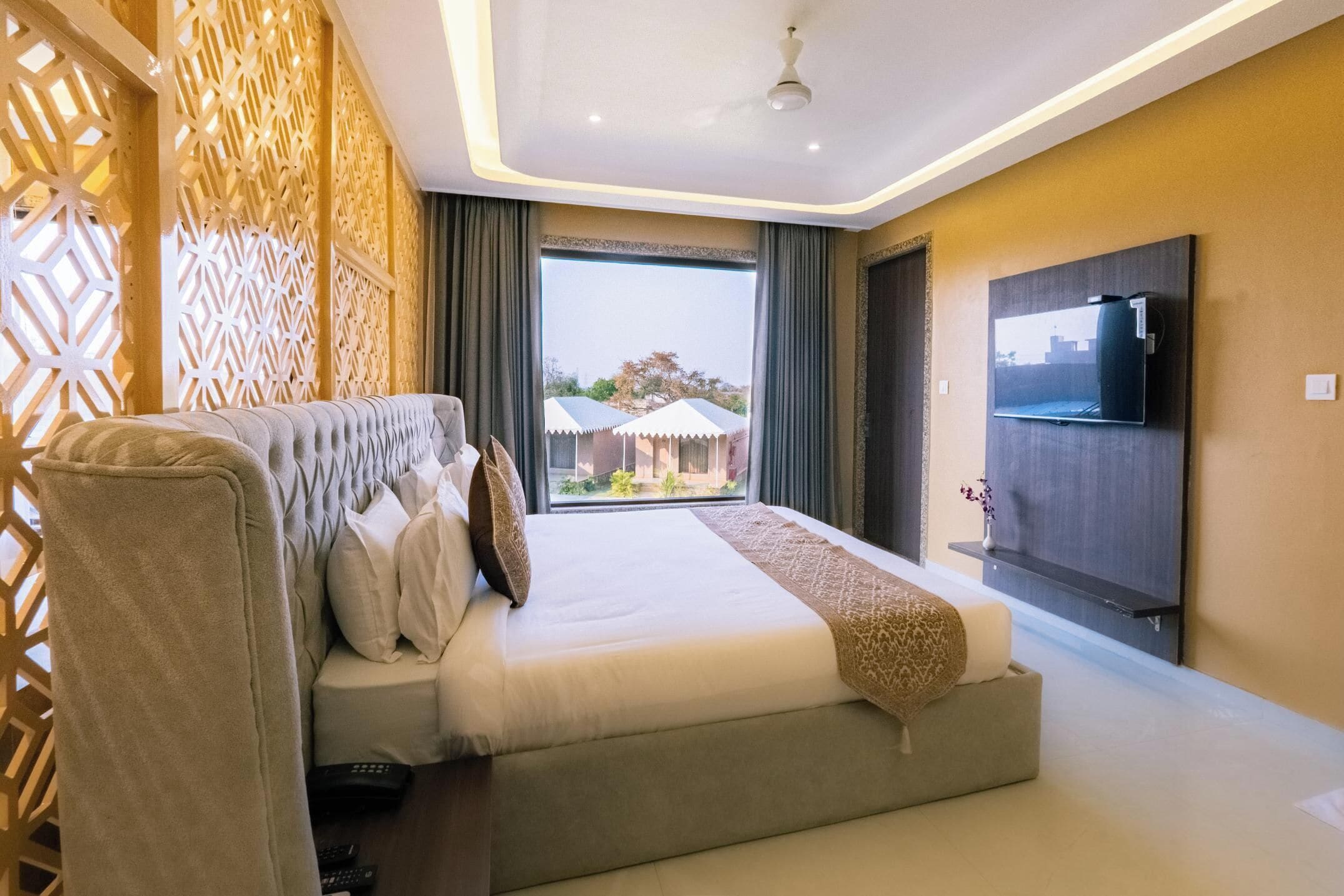 A modern hotel room with a large bed, a TV, and a view of the outside.