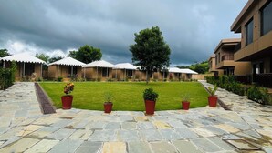 A courtyard with stone flooring, potted plants, and a grassy area. - Imperia Resort by The Sky Imperial (Nathdwara)