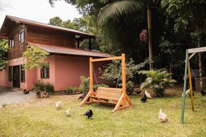 Una casa de madera rústica con un columpio en un jardín exuberante.
