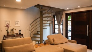 Uma sala de estar moderna com uma escada curva, um sofá e uma mesa de jantar com objetos decorativos.