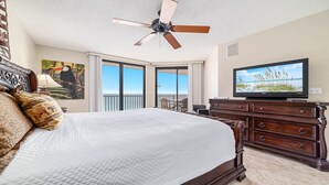 A hotel room with a large bed, a ceiling fan, a television, and a balcony with a view of the beach. - Beachfront 3BR!!  Next door to the Flora-Bama!! (Orange Beach)