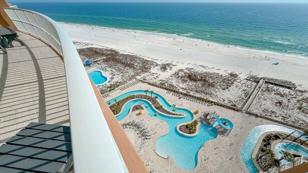 A resort with a pool area featuring winding water features, a beach, and a view of the ocean. - Newest complex on the Alabama Coast!  Lazy River and Slide!! (Orange Beach)