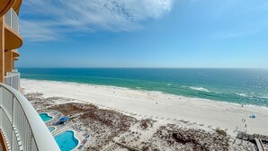 A beach view from a balcony with a pool area and a sandy beach. - Newest complex on the Alabama Coast!  Lazy River and Slide!! (Orange Beach)