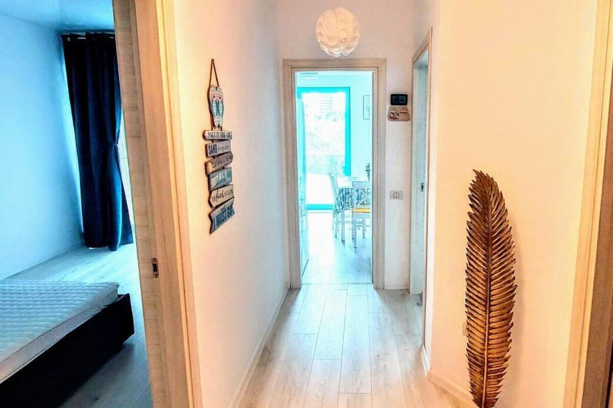 A hallway with wooden flooring, a ceiling light fixture, and a decorative leaf on the wall.