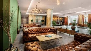 A spacious lobby with leather seating, a reception desk, and a chandelier. - King David standard two bedroom 24 (Tbilisi)