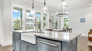 A modern kitchen with a large island, white cabinetry, and a view of the outdoors. - Blue Mountain "Drift Away" | 4BR | Pool Access | 2 BIkes (Santa Rosa Beach)