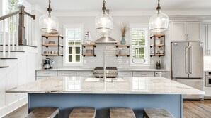 A modern kitchen with a large island, stainless steel appliances, and wooden bar stools. - Blue Mountain "Drift Away" | 4BR | Pool Access | 2 BIkes (Santa Rosa Beach)