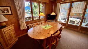 A wooden dining room with a round table, chairs, a TV, and large windows with curtains. - Pre Vert D62, Morgins (Morgins)